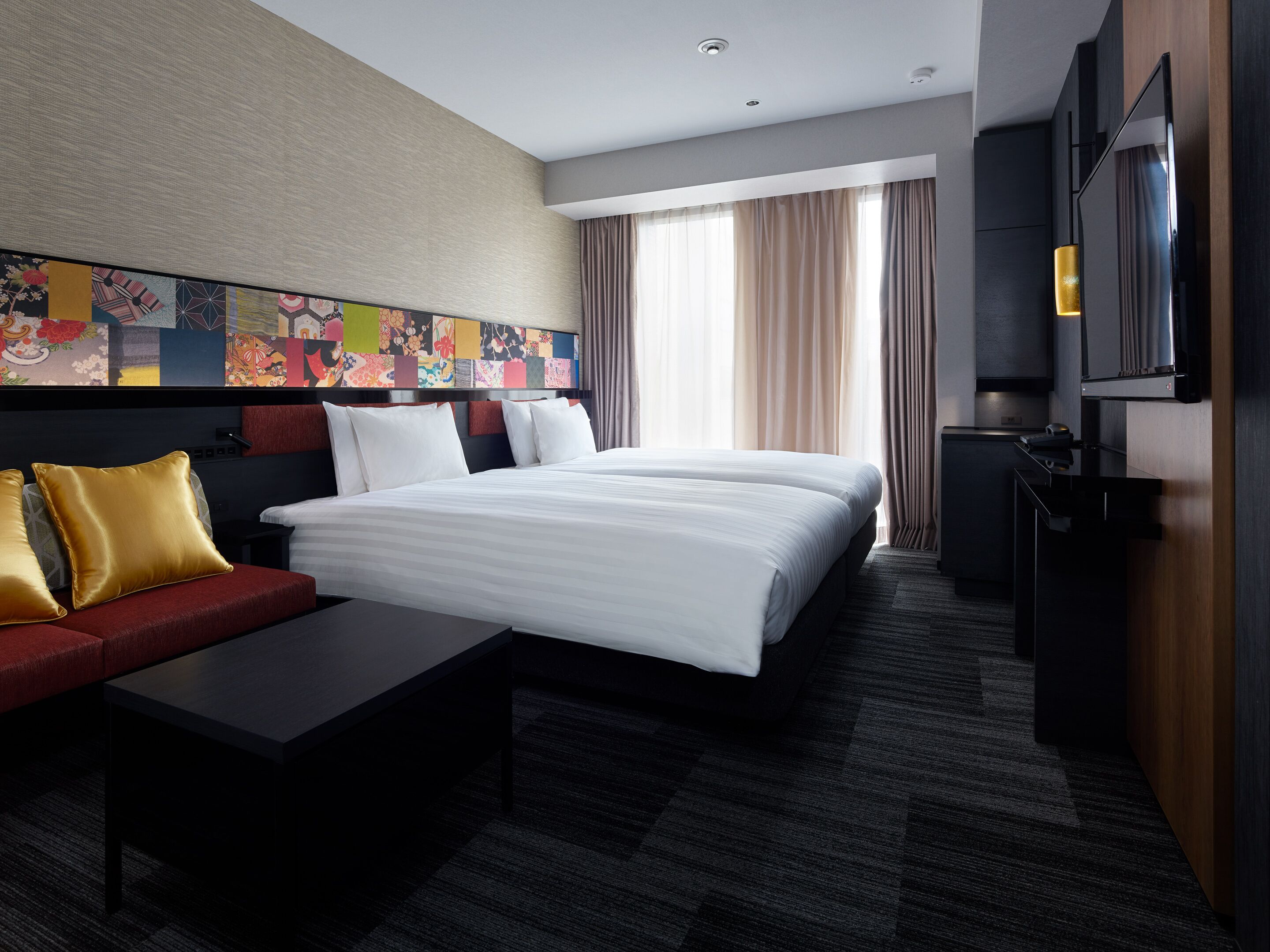A hotel room with a large bed, a sofa, a desk, and a TV.