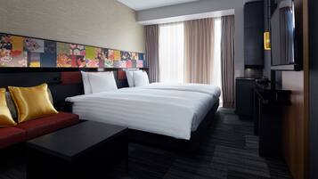 A hotel room with a large bed, a sofa, a desk, and a TV.