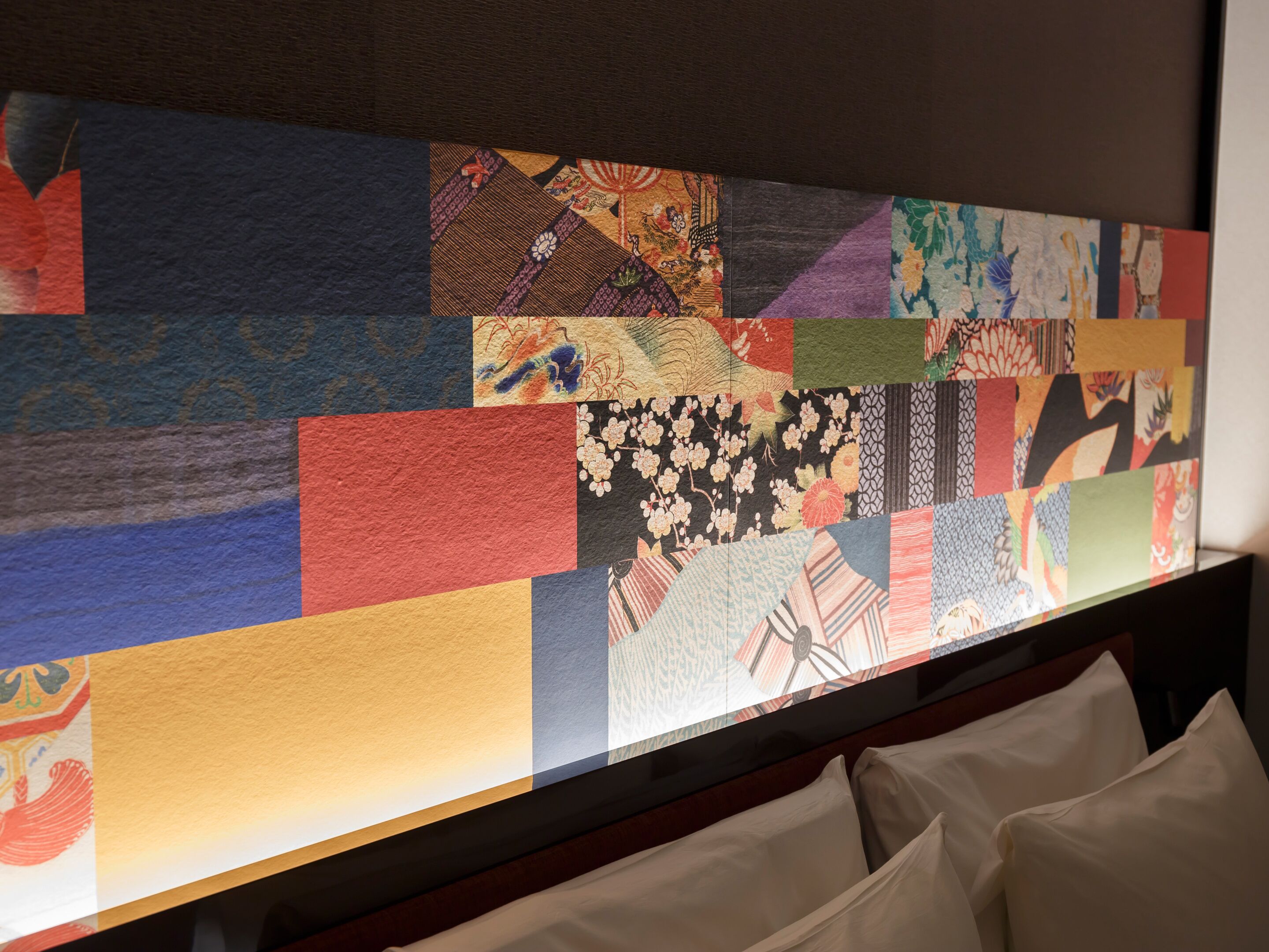 A wall with a patchwork of various fabric patterns, including floral and geometric designs.