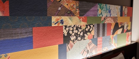 Una pared con un mosaico de diversos diseños de tela, incluyendo motivos florales y geométricos.