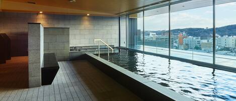 A modern indoor pool with a view of a cityscape through large windows.