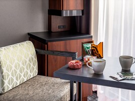 A hotel room with a sofa, a table with coffee cups and tea bags, and a cabinet.