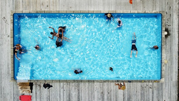 A rectangular swimming pool with a wooden deck surrounding it.
