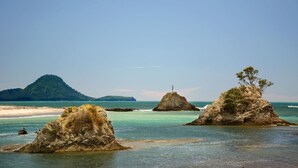 A coastal landscape with rocky formations and a distant mountain.