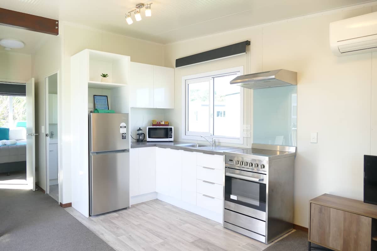 Een moderne keuken met witte kasten, roestvrijstalen apparatuur, een magnetron en een groot raam.