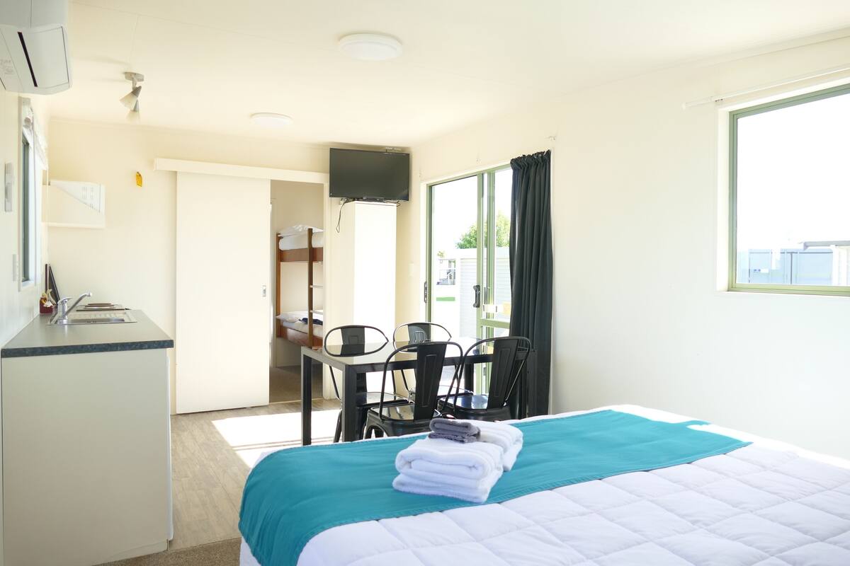 Een hotelkamer met een bed, bureau, stoel, televisie en raam.