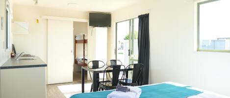 A hotel room with a bed, a desk, a chair, a TV, and a window.