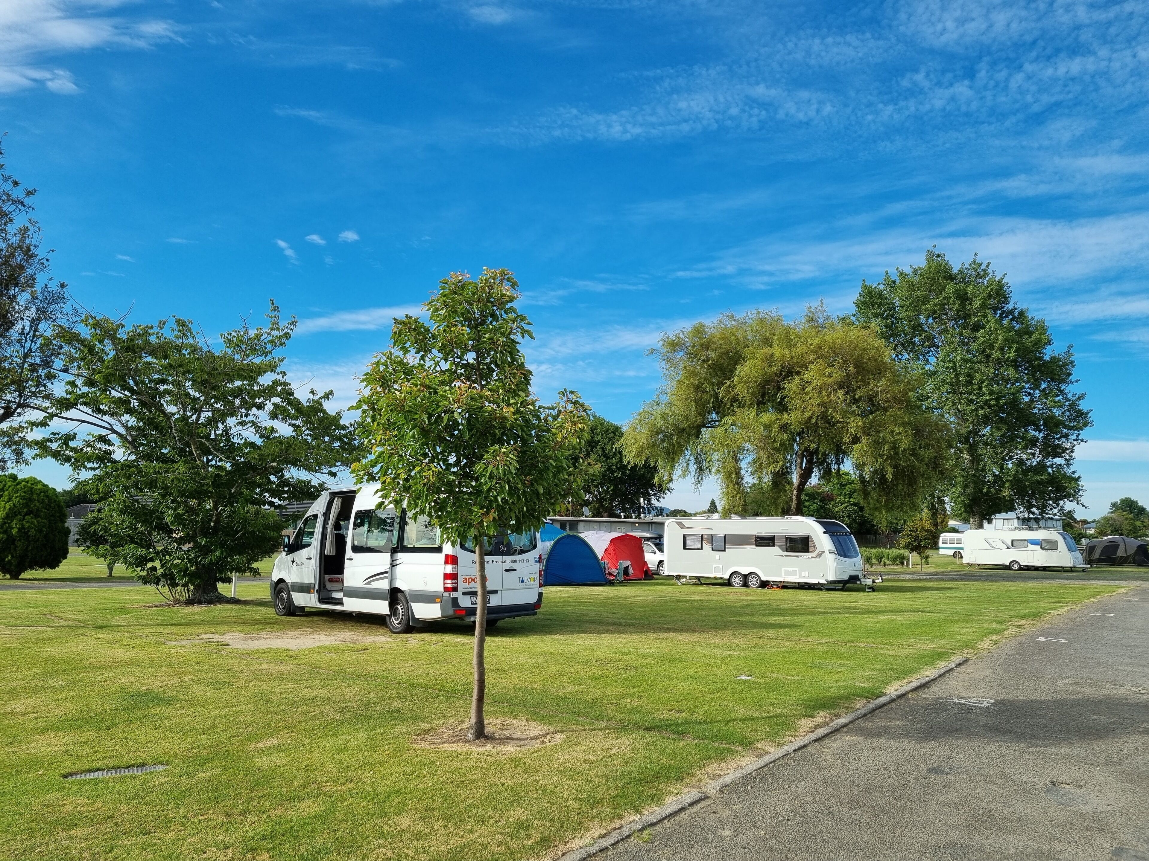Ein Campingplatz mit Wohnmobilen und einem weißen Bus auf einer Wiese.