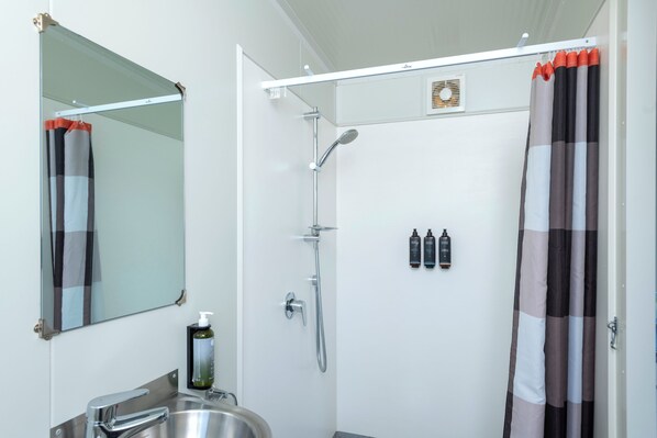 A modern bathroom with a shower, sink, and mirror. - Whakatane Holiday Park (Whakatane)