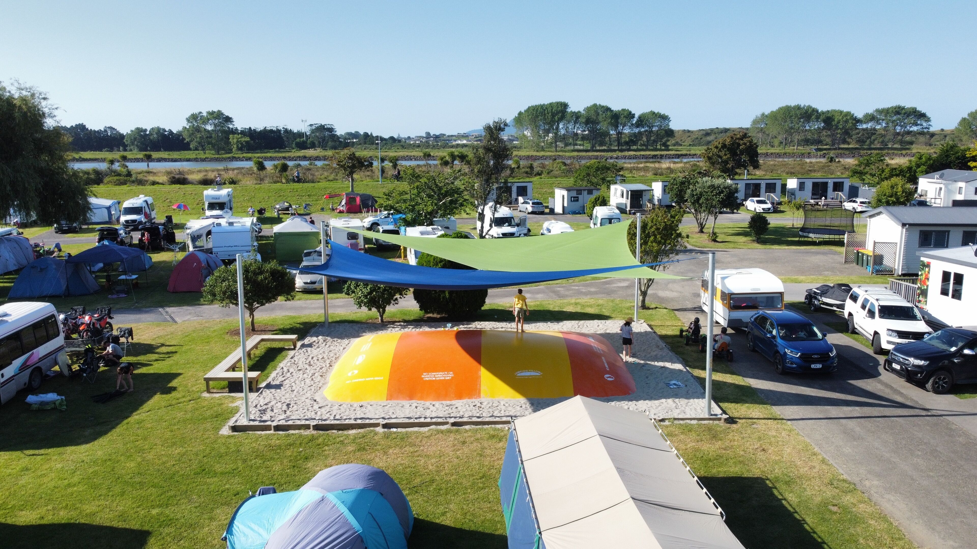 Un terrain de camping équipé d’emplacements pour camping-cars, de zones pour tentes et d’une aire de jeux.