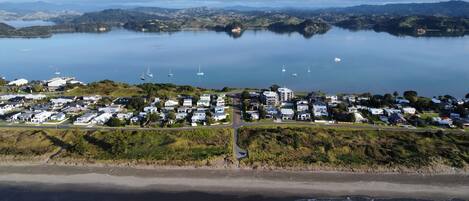 Vista aérea de una zona costera con un puerto deportivo, varias embarcaciones y una área residencial con casas y edificios.