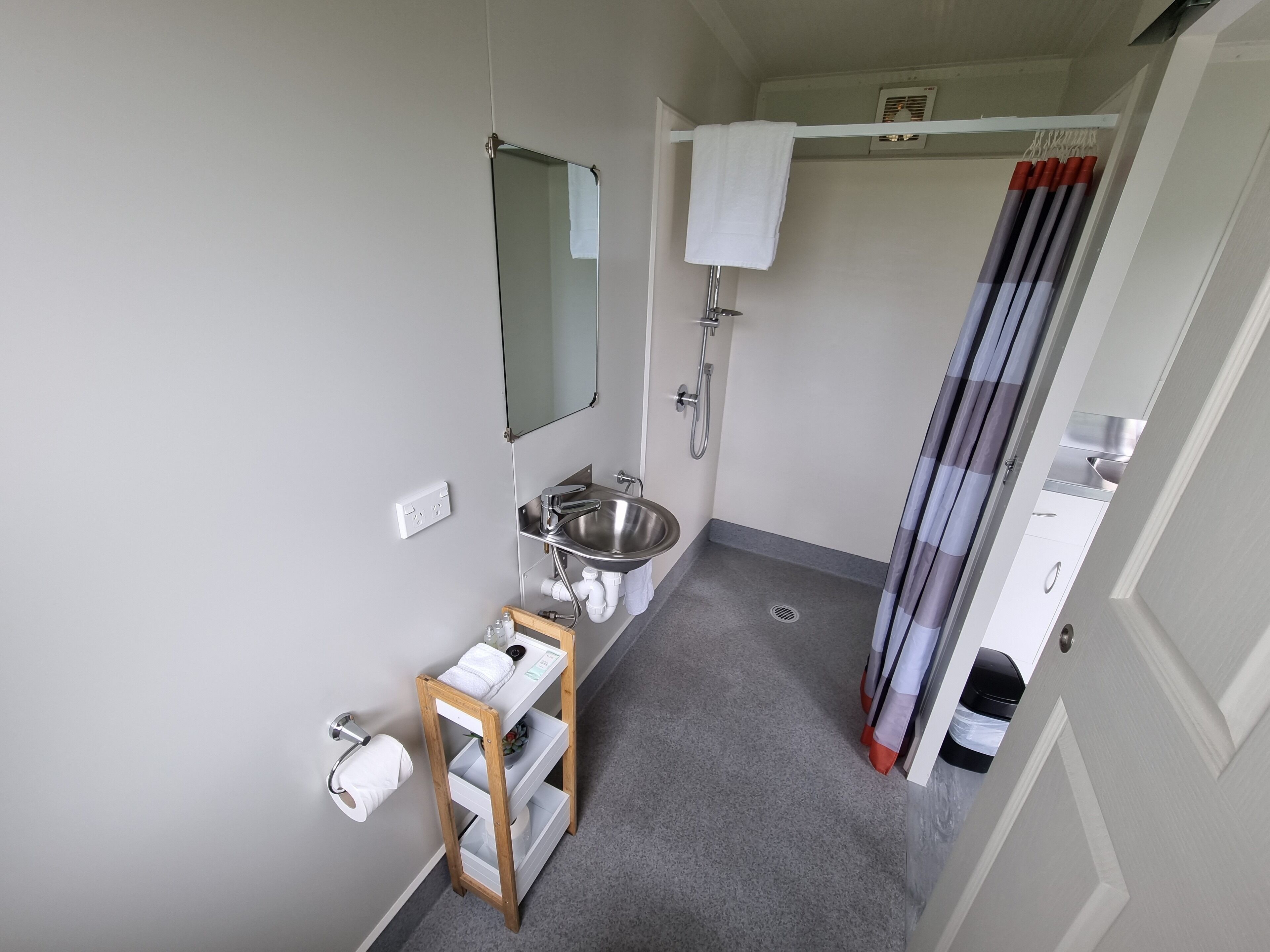 A compact bathroom with a sink, mirror, shower, and toilet.