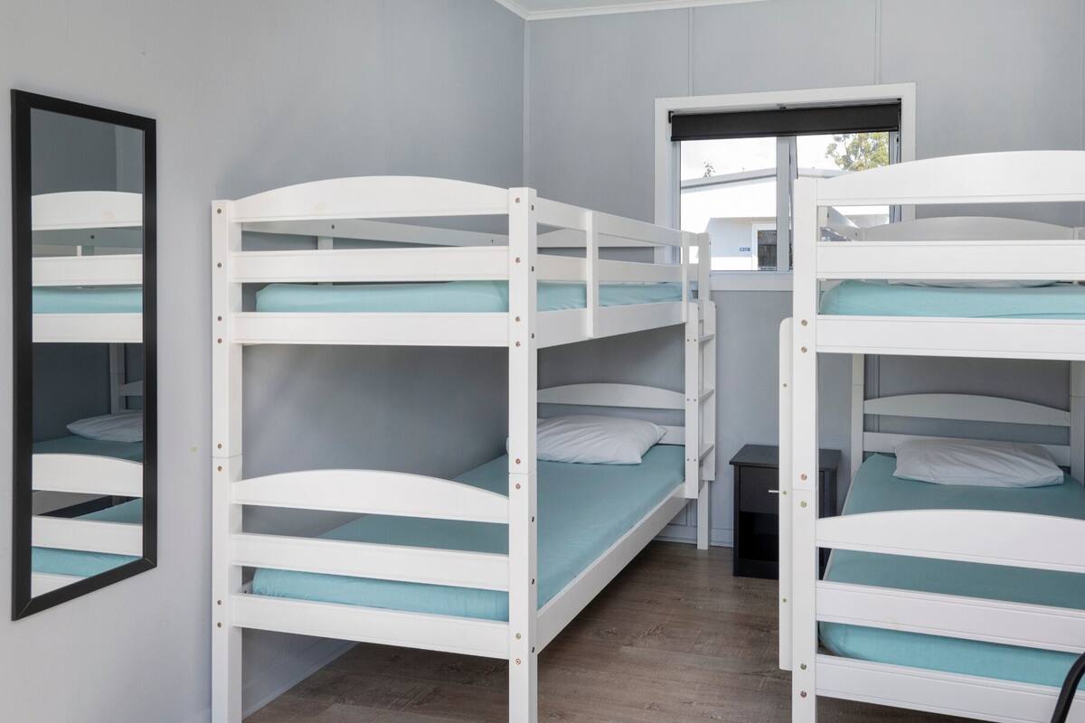 Een kamer met stapelbedden, een spiegel en een raam.