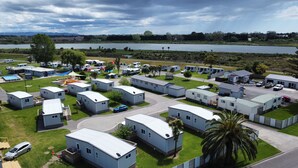 A campground with mobile homes arranged in rows, a lake in the background, and a clear sky.