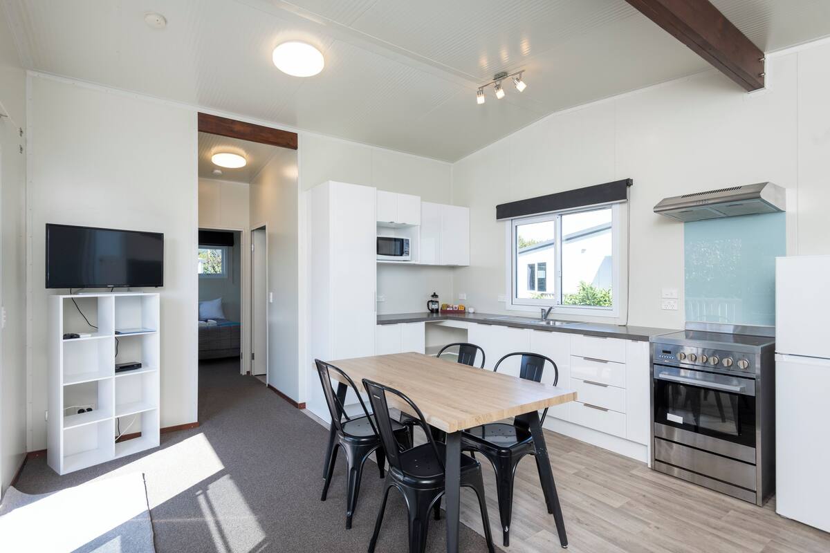 Een moderne keuken met witte kasten, een houten eettafel en zwarte stoelen.
