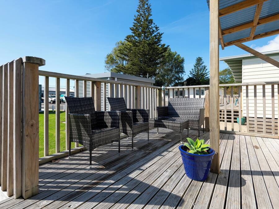 Una terraza de madera con mobiliario exterior y una planta en maceta.