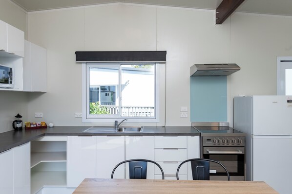 Una cocina moderna con armarios blancos, una estufa de acero inoxidable y una ventana con vistas a un balcón.