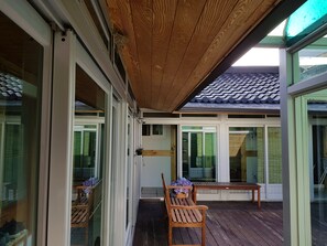 Un espacio al aire libre techado con suelo de madera, una banca y una mesa.