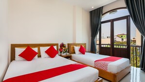 Two single beds with red and white bedding, wooden headboards, and a nightstand with a vase of flowers. - Sunshine Beach Hotel (Da Nang)
