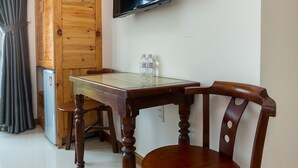 A room with a wooden wardrobe, a TV mounted on the wall, a table with chairs, and a small refrigerator. - Sunshine Beach Hotel (Da Nang)