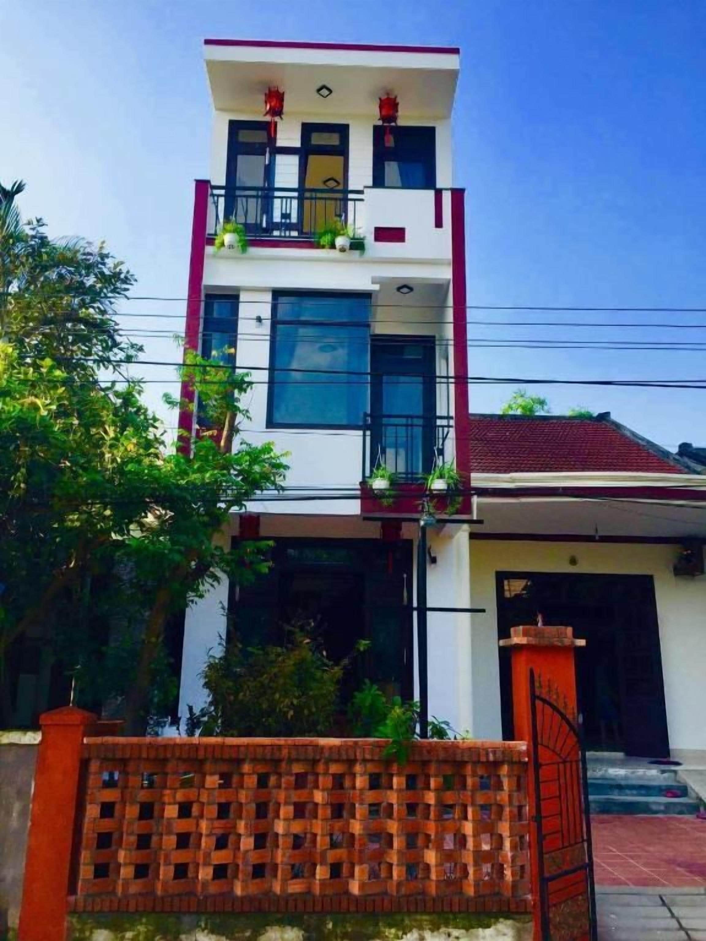 A two-story building with a balcony on the upper floor, a gated entrance, and a red roof.