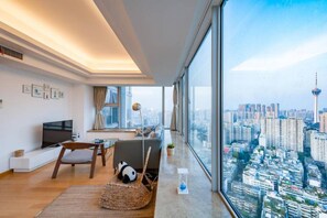 A modern living room with a large window, a television, a sofa, and a decorative panda chair. - Chengdu Ruixi Coast Apartment (Chengdu)