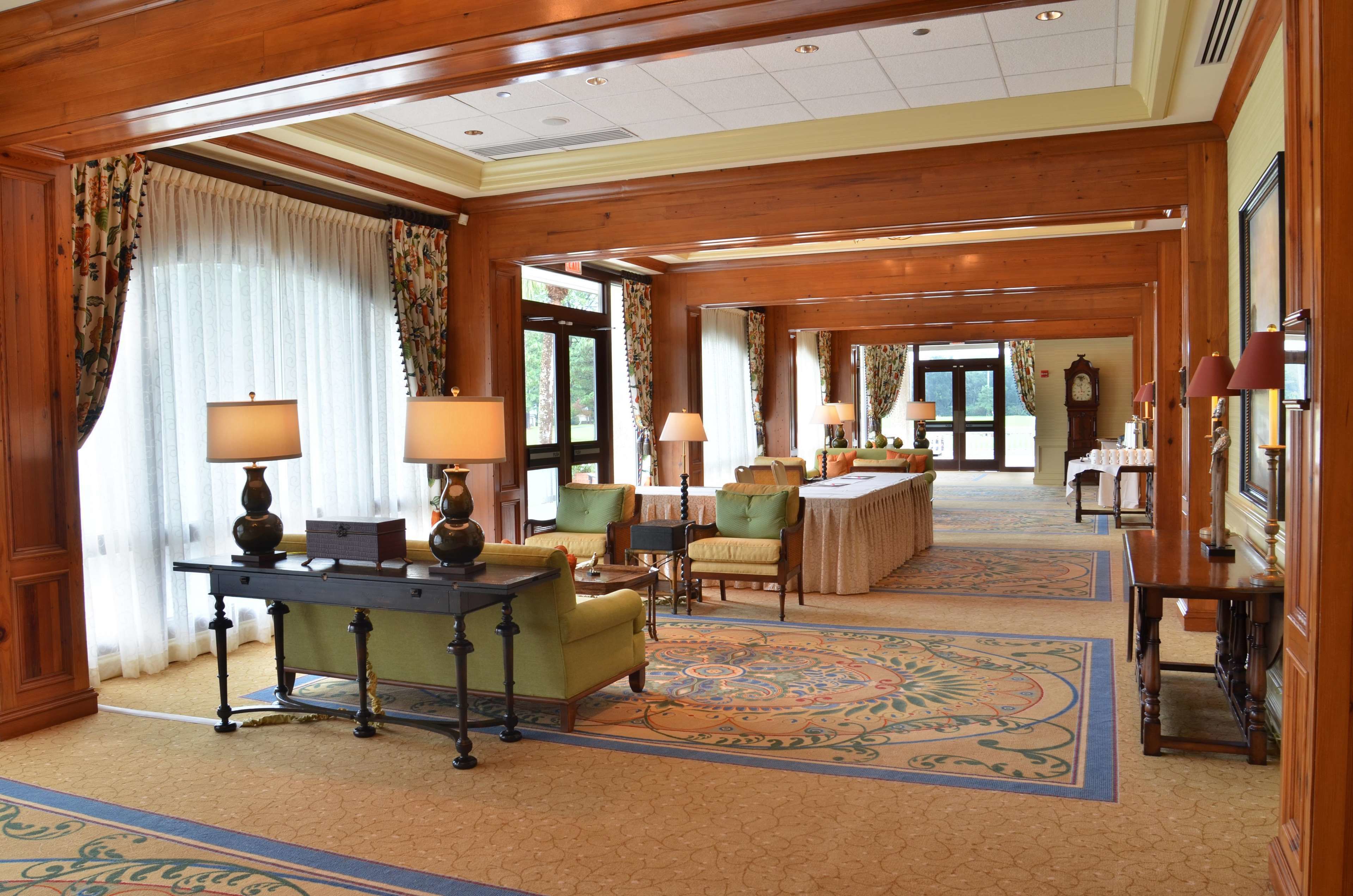 Hall d'albergo con pannelli in legno, reception, area salotto e un tappeto decorato.