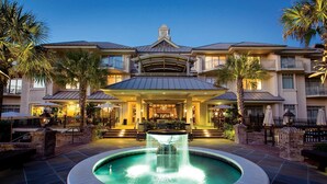 A hotel with a central courtyard featuring a fountain, outdoor seating, and palm trees. - The Inn & Club at Harbour Town (Hilton Head Island)