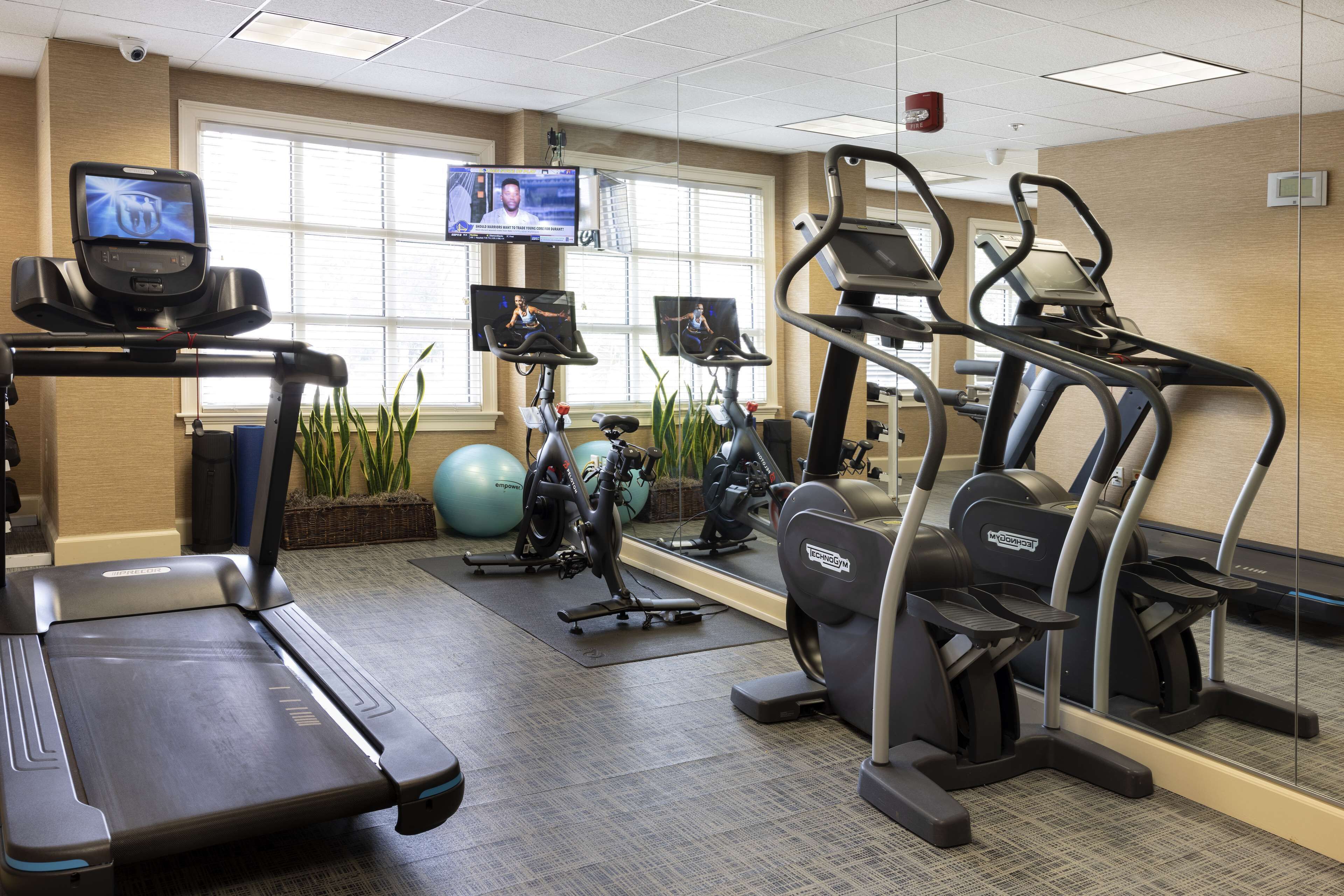 A gym with treadmills, stationary bikes, and exercise balls.