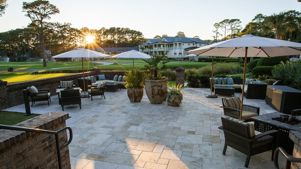An outdoor patio area with seating, umbrellas, and a view of a golf course. - The Inn & Club at Harbour Town (Hilton Head Island)