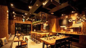A modern restaurant with wooden decor, a bar area, and multiple seating options. - FOCUS Kuramae - Hostel (Tokyo)
