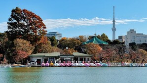A waterfront area with a row of colorful boats, a traditional building with a green roof, and a modern tower in the background. - FOCUS Kuramae - Hostel (Tokyo)