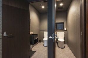 Un baño moderno con dos inodoros, un lavabo y un espejo.
