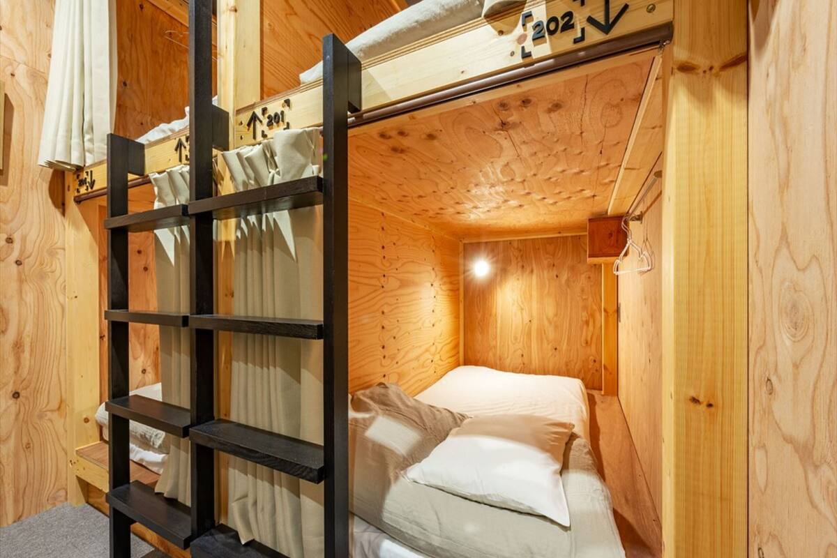 Dormitorio con literas, una escalera, paredes de madera y una ventana pequeña.