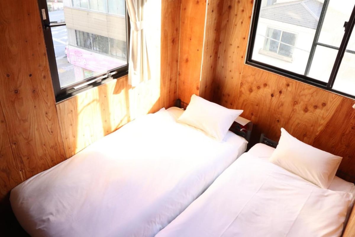 A small, cozy room with two beds and wooden walls.