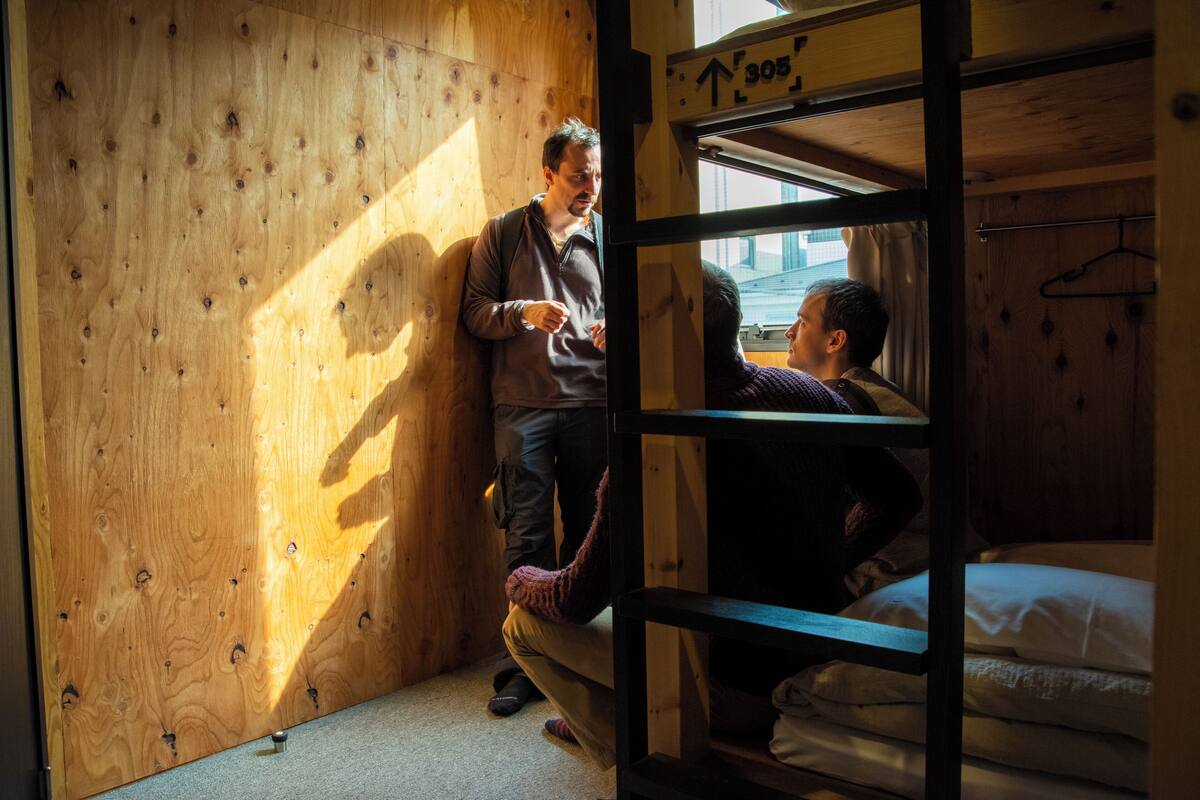 Interior de madera con literas, una ventana y una puerta con un letrero.