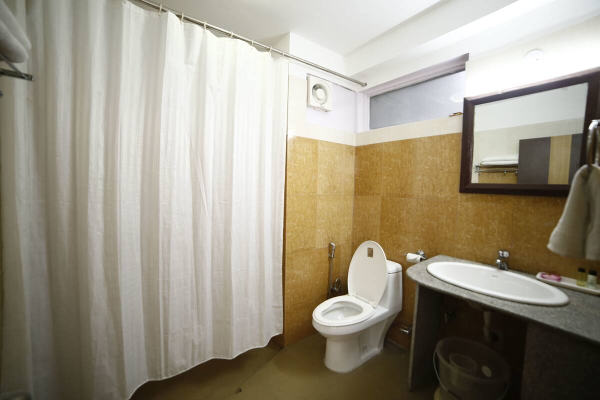 A bathroom with a toilet, sink, mirror, and shower curtain.