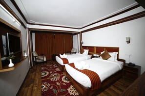 A hotel room with two beds, a wooden floor, a red carpet, and a wooden headboard. - Hotel Sikkim Tourist Centre (Gyalshing)