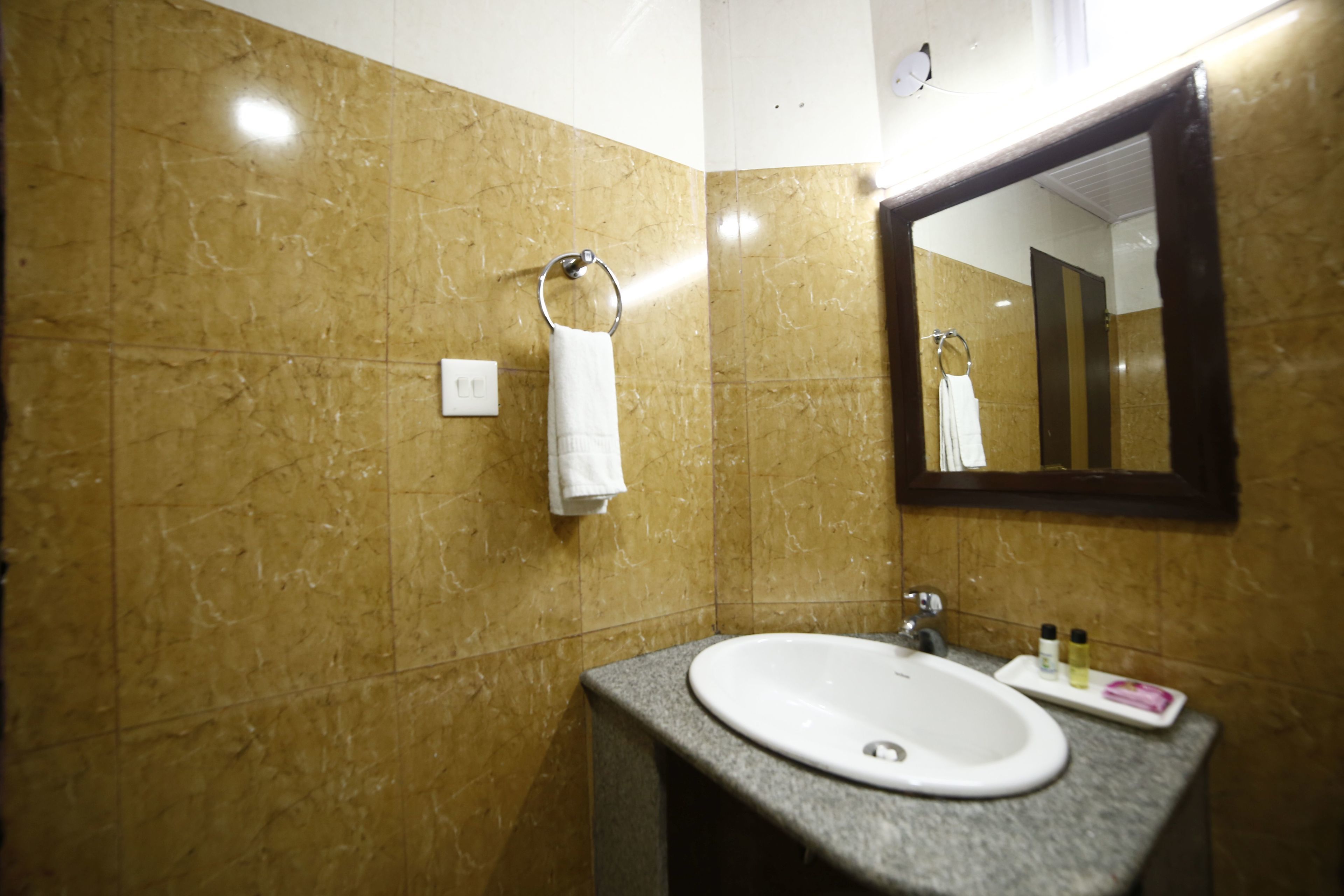 A bathroom with a marble wall, a sink, a mirror, and a towel ring.