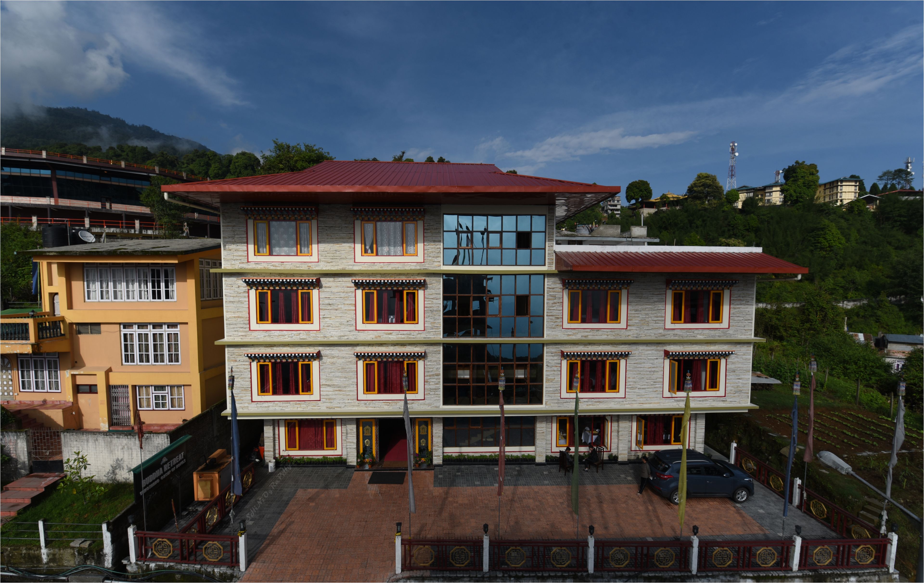 A multi-story building with a red roof, large windows, and a paved entrance area.