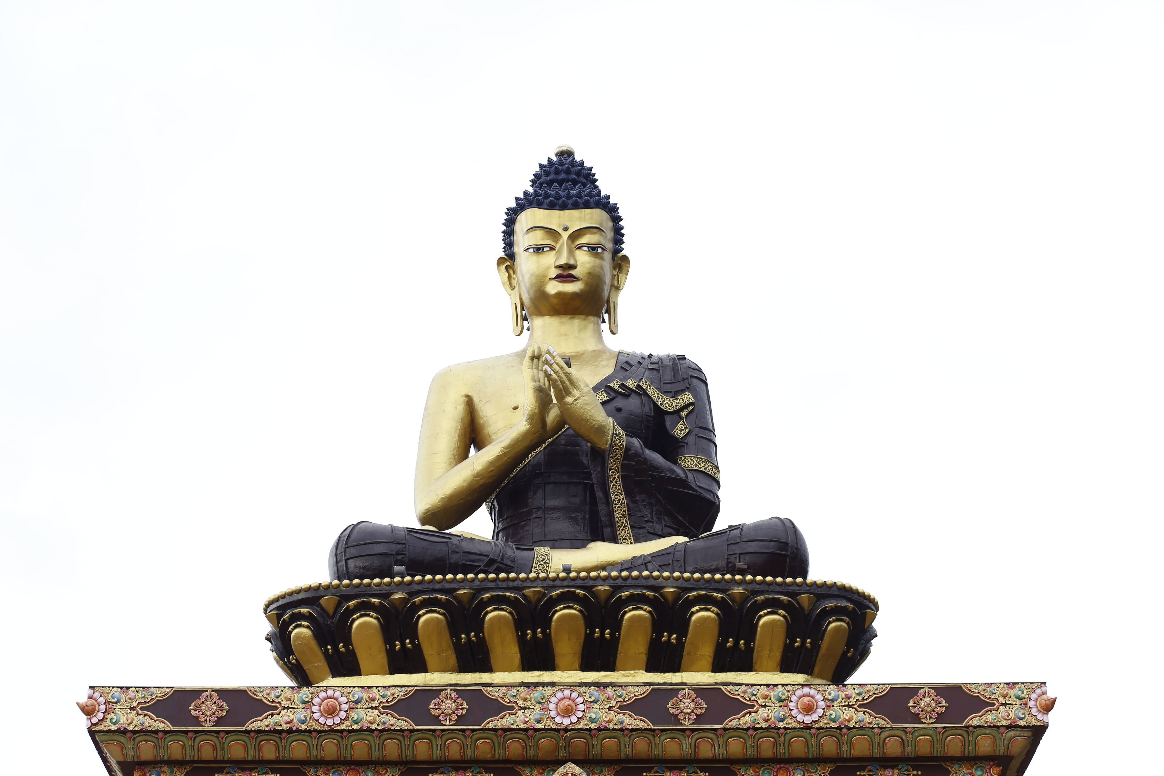 Une grande statue assise, dont le socle est orné de motifs complexes.