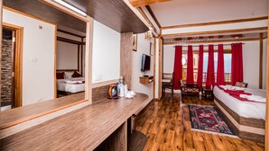 A hotel room with a wooden ceiling, a large mirror, a wooden desk, a bed with red curtains, and a small table with a chair. - Buddha Retreat (Namchi)