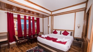 A bedroom with a large bed, wooden flooring, red curtains, and a view of the mountains. - Buddha Retreat (Namchi)