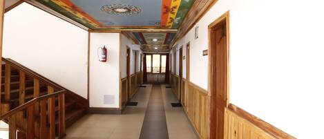 A hallway with wooden paneling, a tiled floor, and a colorful ceiling with traditional patterns.