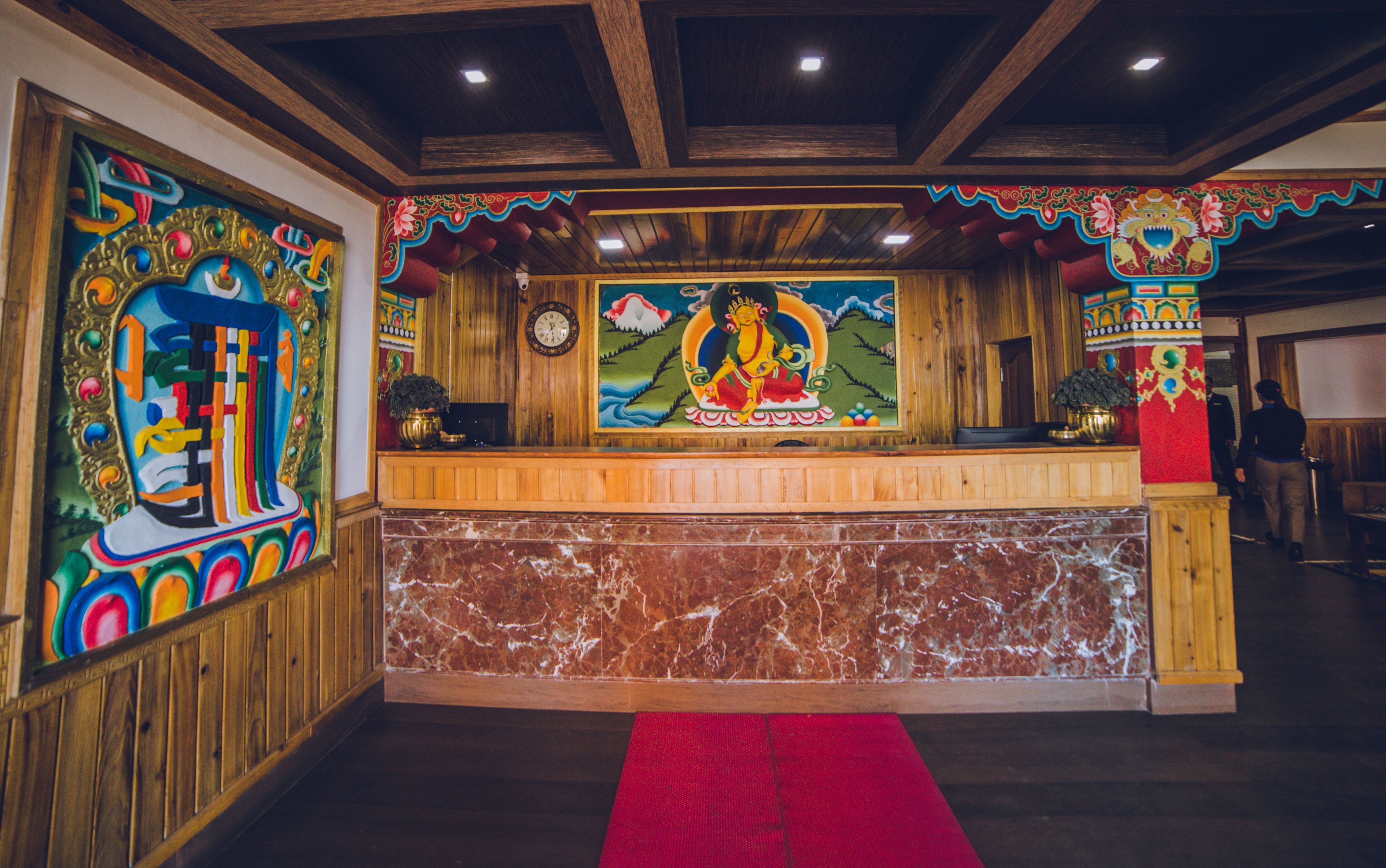 A reception area with a wooden counter, a red carpet, and colorful wall decorations.