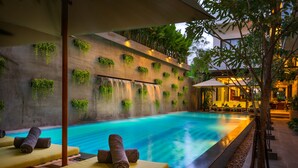 A poolside area with lounge chairs and a wall with hanging plants. - Gold Smith Residence (Siem Reap)