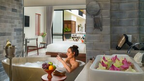 A woman relaxing in a bathtub with fruits and a glass of wine, a hairdryer, and a towel rack on the wall. - Gold Smith Residence (Siem Reap)