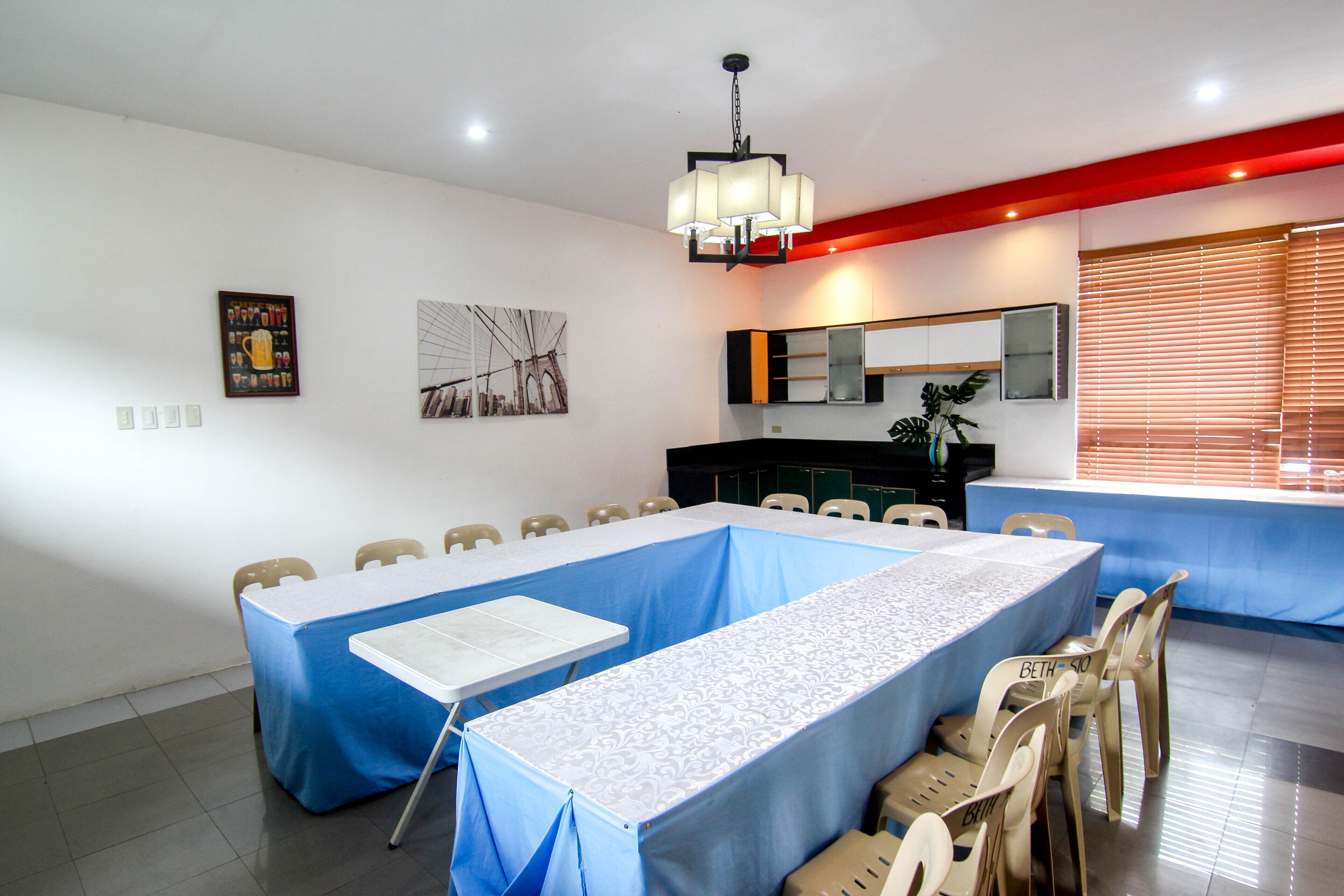 A conference room with a long table, chairs, a whiteboard, and a large mirror.