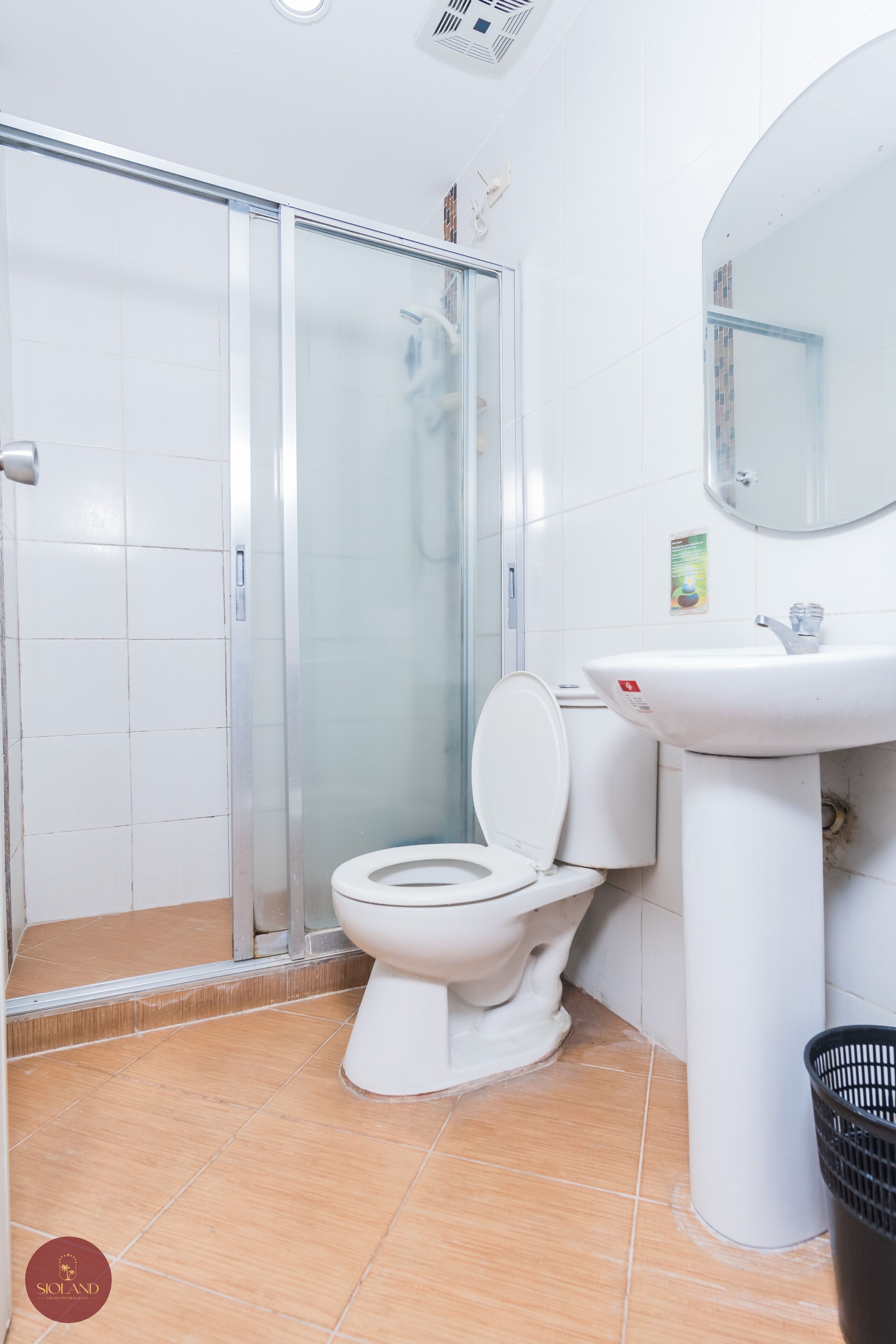 Un baño con cabina de ducha de vidrio, inodoro y lavamanos con espejo.