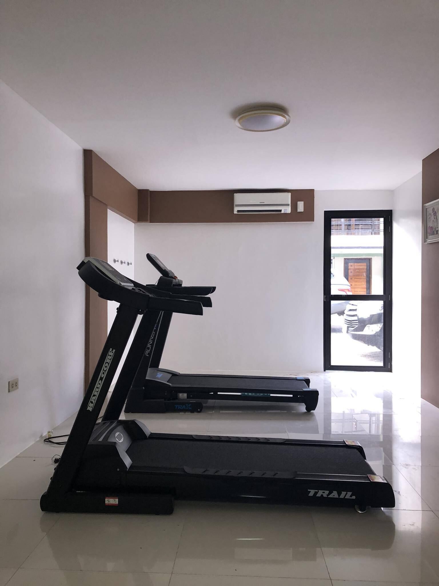 A room with two treadmills, a white ceiling, and a door leading outside.